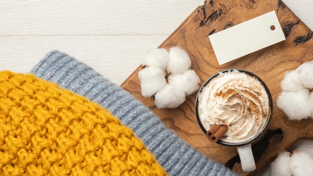 Top view of sweater with cotton and cup of coffee with whipped cream