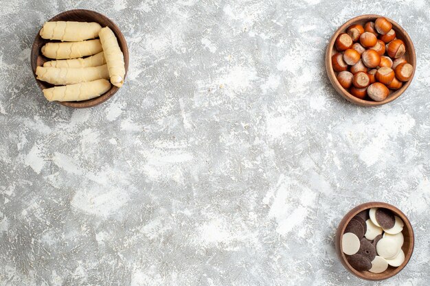 Вид сверху сладкие рогалики с печеньем и орехами на белой поверхности