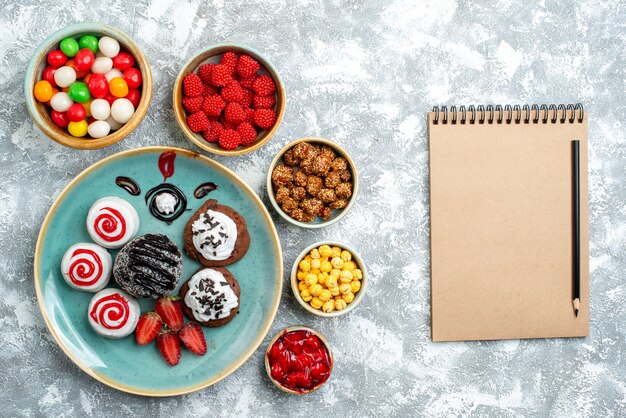 Top view sweet biscuits with chocolate cake and candies on light white background candy sugar biscuit cake sweet tea