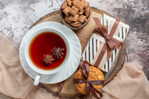 Top view sweet biscuits with present and cup of tea on light table