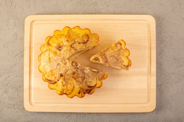 A top view sweet cake delicious yummy choco cake sliced on the cream colored square desk on the grey background sugar tea biscuit bake