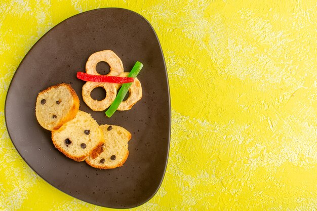 Top view of sweet cake slices inside brown plate with marmalade on the yellow surface