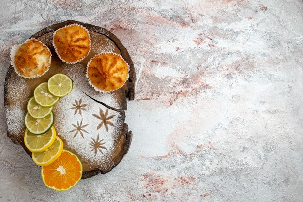 Top view sweet cakes with lemon slices on light white surface