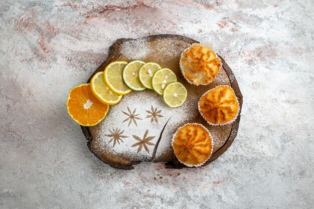 Top view sweet cakes with lemon slices on the white surface