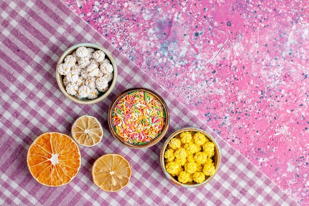 Top view sweet candies colorful confitures on pink desk