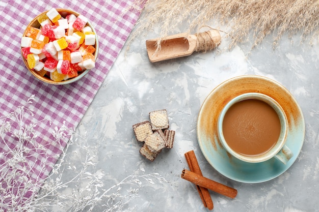 Вид сверху сладкие конфеты с корицей и молочным кофе на светлом фоне конфеты сладкий сахар фото цвет