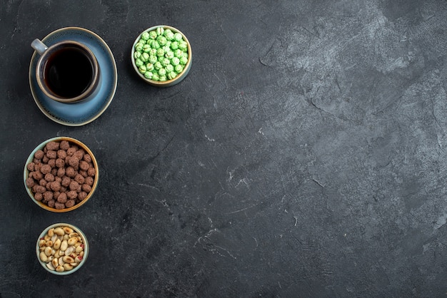 Top view sweet candies with cup of coffee on dark-grey background