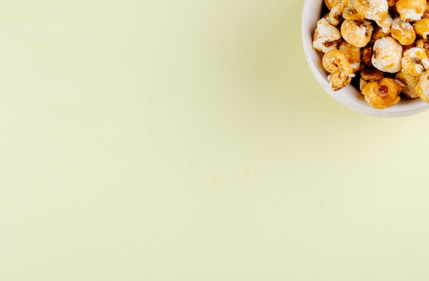 Top view of sweet caramelized pop corn in a bowl on white background with copy space