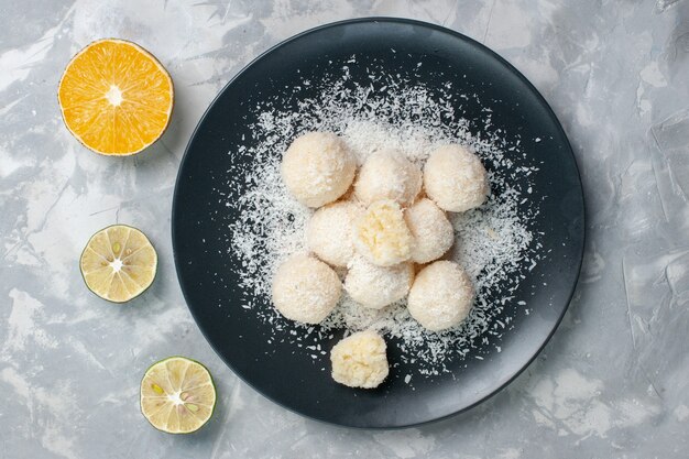 Top view sweet coconut candies inside plate on white