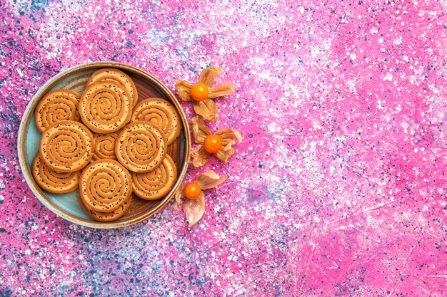 Top view of sweet cookies inside plate on the pink surface