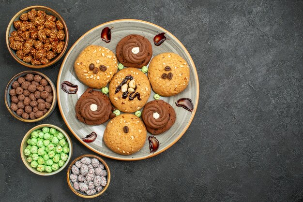 Biscotti dolci di vista superiore con le caramelle sul tè della torta del biscotto dolce del biscotto dello zucchero della scrivania grigia