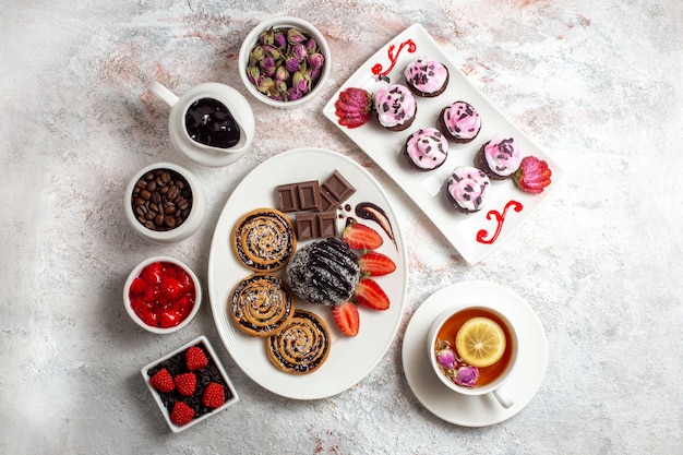 Top view sweet cookies with chocolate cake and tea on the white background cookie biscuit sugar tea sweet cake