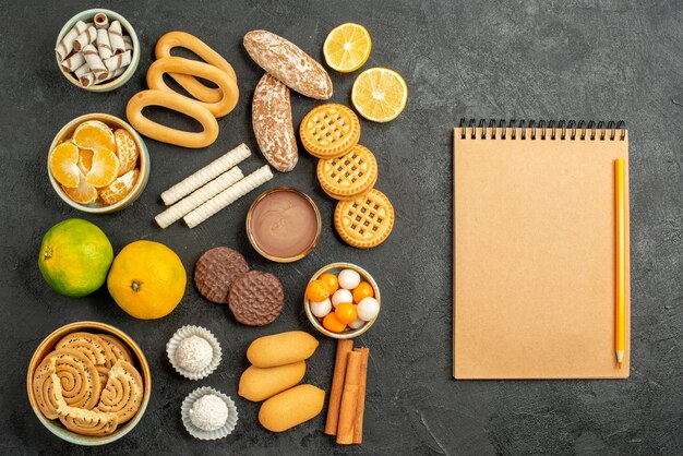 Top view sweet cookies with fruits and biscuits on grey background