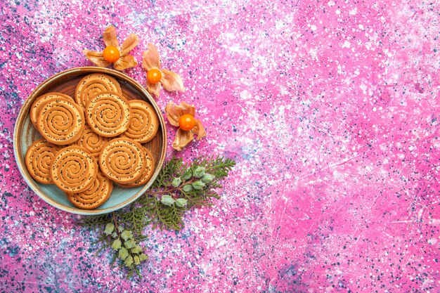 Вид сверху сладкого печенья с физалисом на светло-розовой поверхности