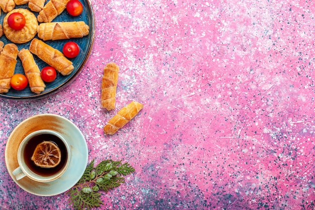 Free photo top view sweet delicious bagels baked pastries inside tray with plums on the pink desk