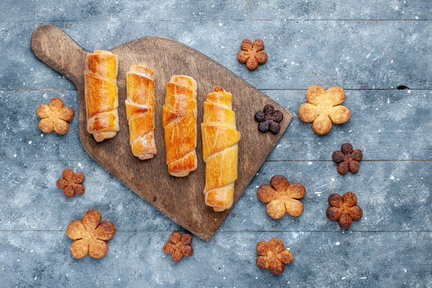 Top view sweet delicious bangles with filling along with cookies on the grey wooden background sweet sugar bake pastry