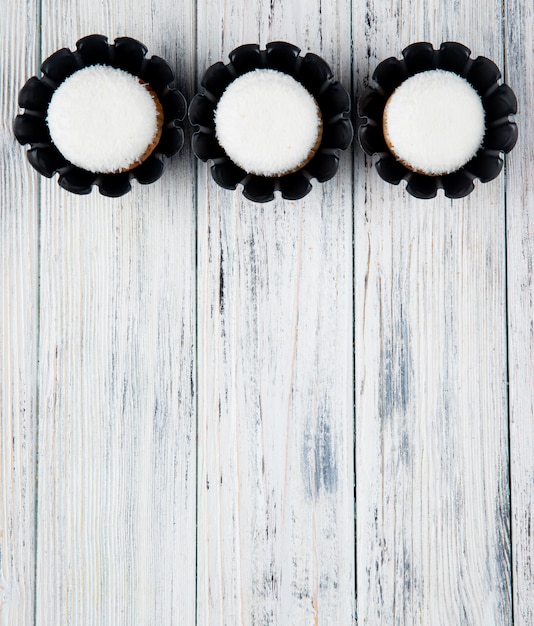 Free photo top view of sweet delicious muffins with coconut flakes isolated on rustic background with copy space