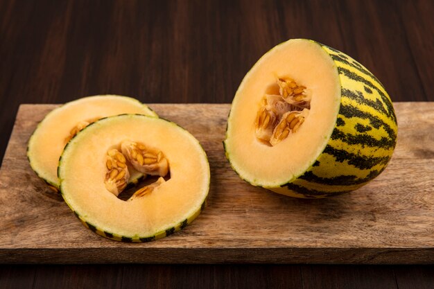 Top view of sweet fresh slices of cantaloupe melon on a wooden kitchen board on a wooden wall