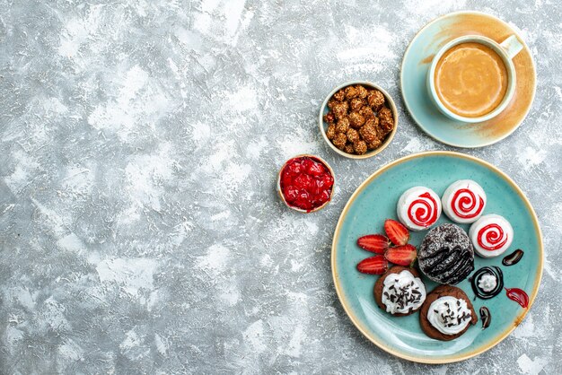 上面図白い背景の上のコーヒーのカップと甘い小さなケーキケーキ甘いビスケットシュガーコーヒークッキ