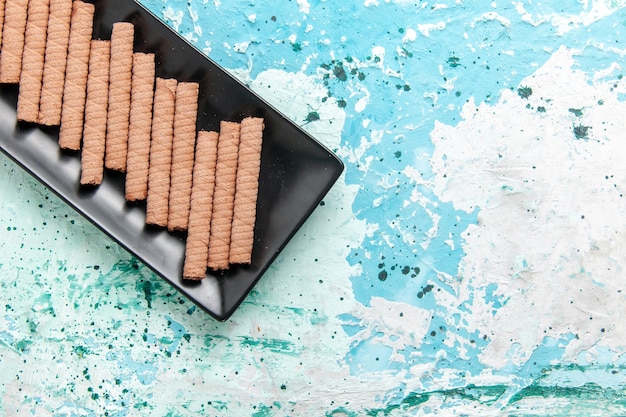 Vista dall'alto dolci biscotti lunghi all'interno di una tortiera nera su sfondo azzurro