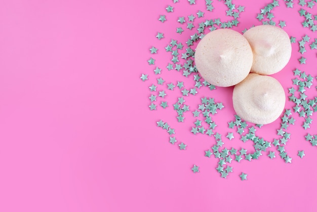 A top view sweet meringues along with star formed candies on pink desk, sweet sugar candy color