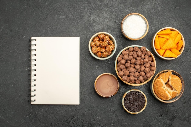 Top view sweet nuts with cocoa flakes and cips on dark grey surface snack milk meal breakfast nut