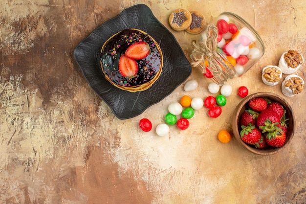 Вид сверху сладкие блины с красочными конфетами на деревянном столе