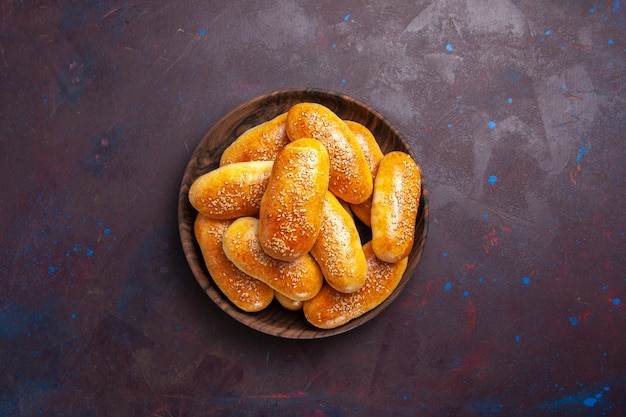 Top view sweet patties delicious baked dough for tea on a dark background meal pastry dough tea food patty