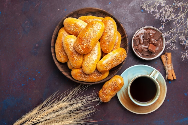 Top view sweet patties with cup of tea and chocolate on the dark background meal pastry dough tea food patty