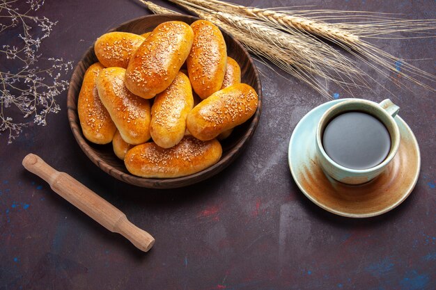 Top view sweet patties with cup of tea on a dark background pastry dough meal food patty tea