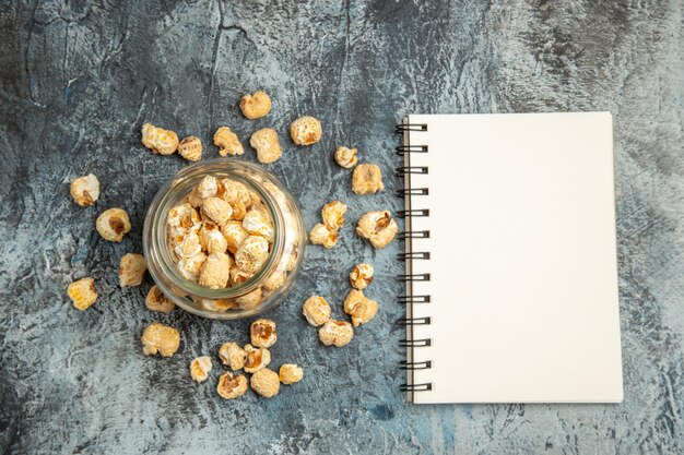 Top view sweet popcorn with notepad on light surface