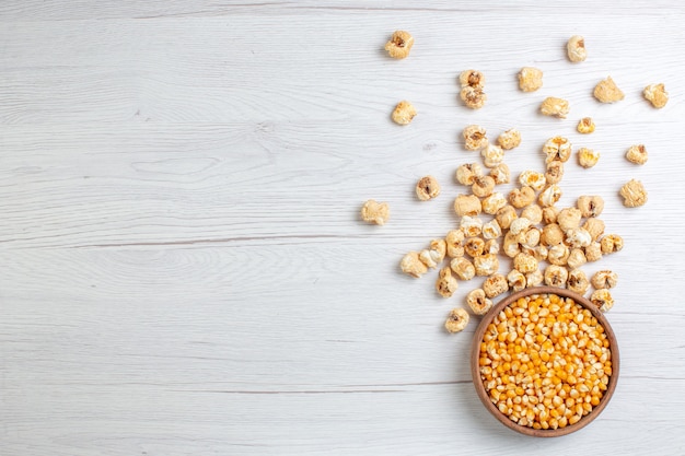 Top view sweet popcorn with raw corns on light surface