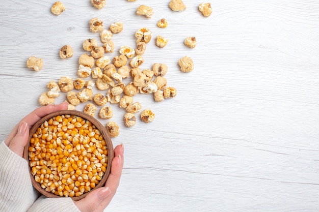 Foto gratuita popcorn dolce vista dall'alto con semi crudi su superficie chiara