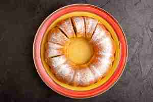 Foto gratuita un dolce rotondo dolce di vista superiore con la torta isolata deliziosa dolce affettata polvere di zucchero dentro il piatto e il biscotto di zucchero grigio del biscotto del fondo