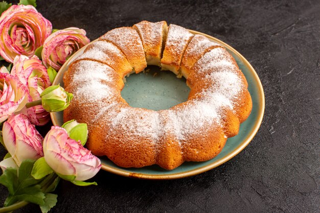 A top view sweet round cake with sugar powder on top sliced sweet delicious isolated inside plate along with flowers and grey background biscuit sugar cookie