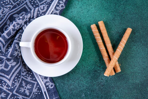 Top view sweet tubes with a cup of tea on green