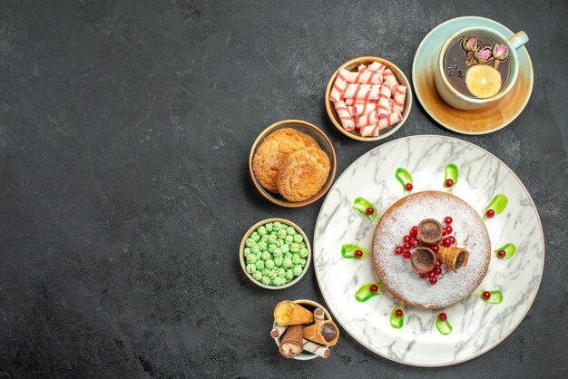 Top view sweets cake with berries sweets waffles cookies a cup of tea