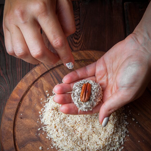 Сладкие конфеты ручной работы из орехов, сухофруктов и меда на темной деревянной поверхности.