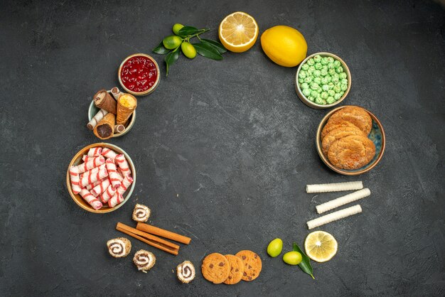 Top view of sweets jam citrus fruits with leaves sweets cookies are laid out in a circle