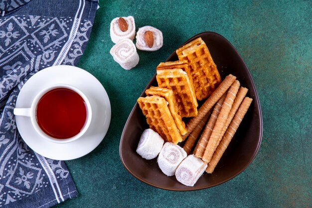 Dolci di vista superiore waffles panini dolci e marmellata con una tazza di tè sul verde