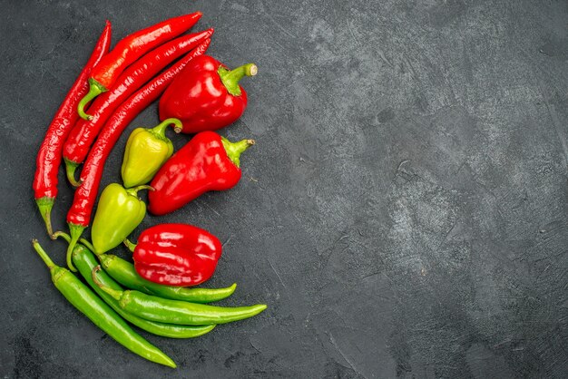 Top-view symmetric framed peppers with its bright colors on dark surface with free space