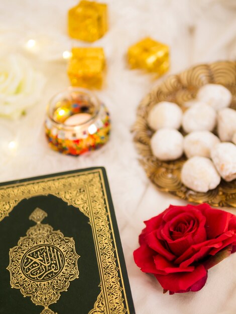 Top view table arrangement with quran, roses and pastries