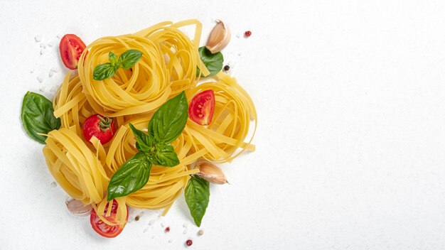 Top view of tagliatele pasta with basil and tomatoes with copy space