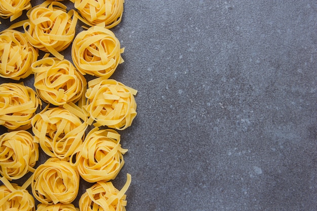 Top view tagliatelle pastas on gray background. horizontal space for text