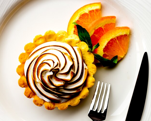Top view tartlet with meringue and slices of orange and mint