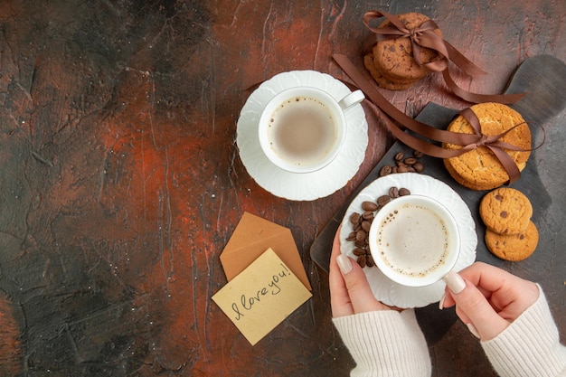 暗い背景の上のコーヒーのカップとおいしいビスケットの上面図クッキー甘いお茶のカップルはケーキの朝の色が大好きです