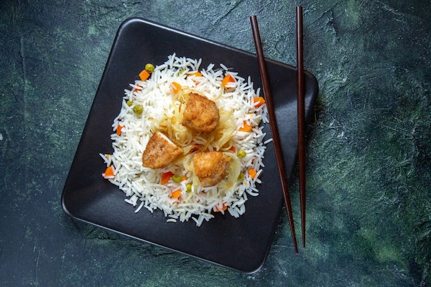 暗い机の上のプレートの中に豆と肉が入った上面図おいしいご飯