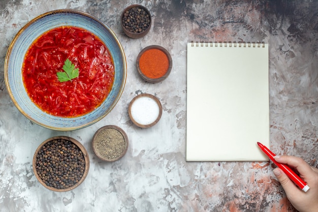 Top view of tasty borsch ukrainian beet soup with seasonings on white surface