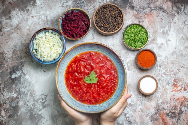 Top view of tasty borsch with seasonings and greens on white surface