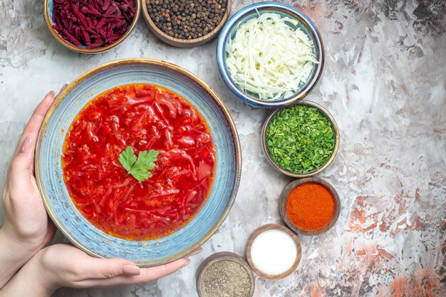 Top view of tasty borsch with seasonings on white surface